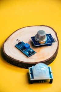 A photo of modern robotics sensors displayed on a wooden slice against a vibrant yellow background.
